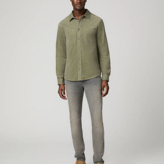 Man wearing green shirt and grey jeans and brown shoes