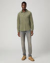 Man wearing green shirt and grey jeans and brown shoes