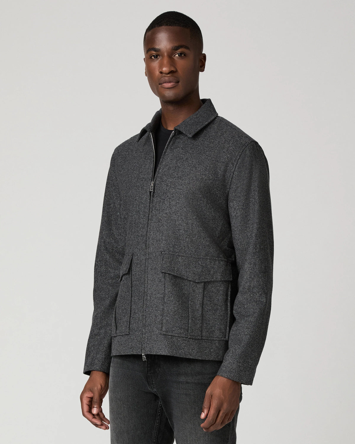 Man wearing grey zip jacket and black jeans  side view