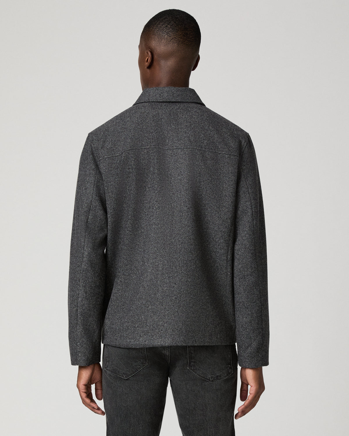 Man wearing grey zip jacket and black jeans  rear view