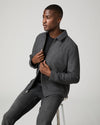Man sat down wearing grey zip jacket and black jeans 