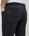 Close-up back view of a person wearing dark charcoal corduroy trousers, showing the back pocket detail and waistband.