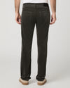 Rear view of a person wearing dark charcoal corduroy trousers, a white t-shirt, and beige platform shoes against a light gray studio background.