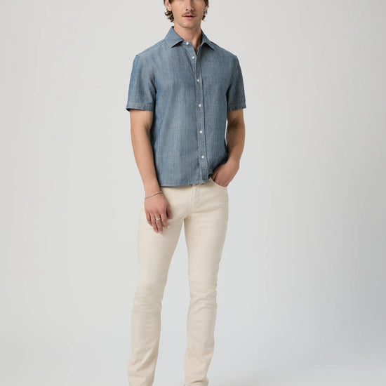 Man wearing a blue checkered shirt and beige pants on a white background from Paige