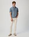 Man wearing a blue checkered shirt and beige pants on a white background from Paige