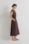 Woman wearing a brown linen dress against a plain background