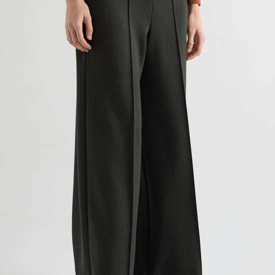 Person wearing dark green wide-leg pants on a light gray background