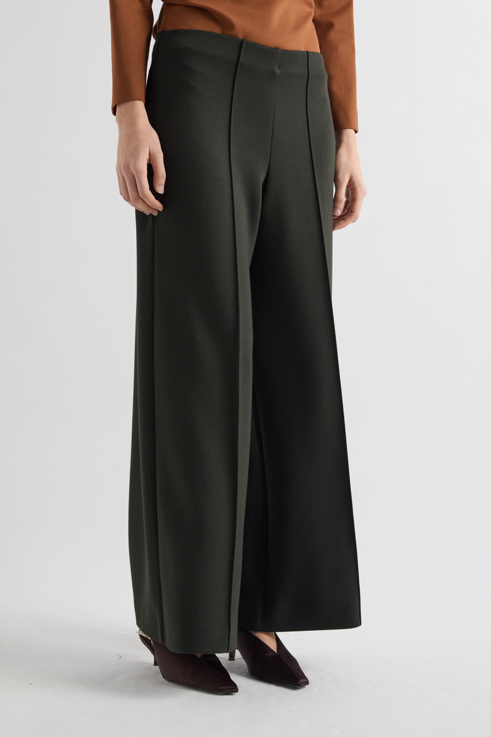 Person wearing dark green wide-leg pants on a light gray background
