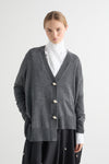 Person wearing a gray cardigan with white buttons on a white background