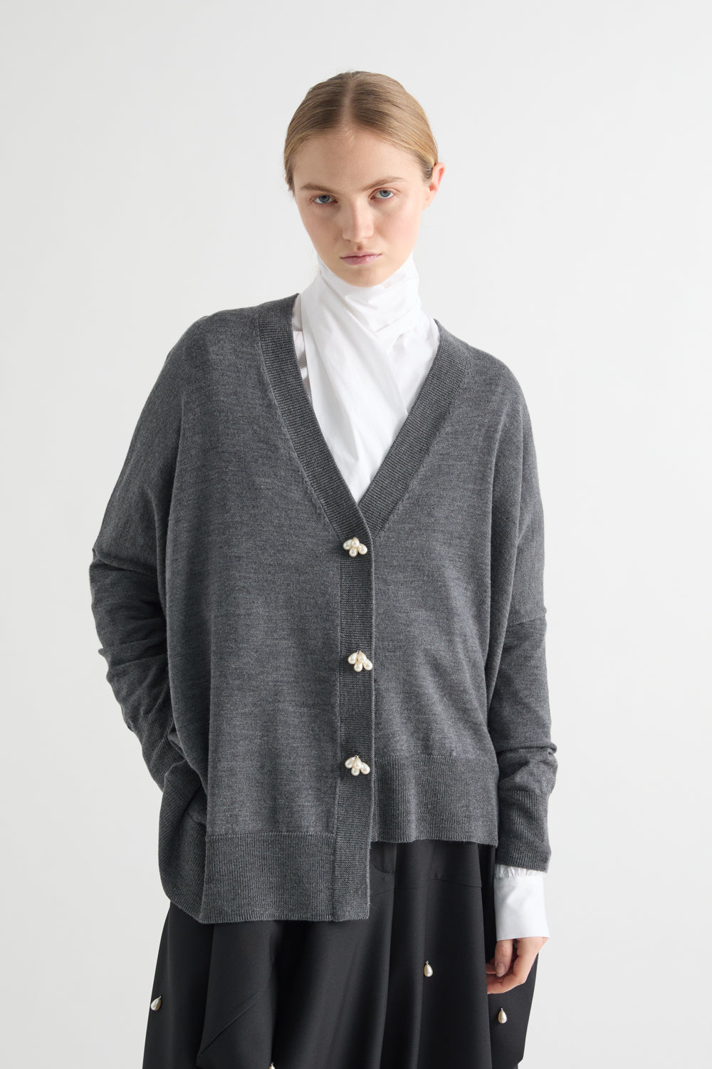 Person wearing a gray cardigan with white buttons on a white background