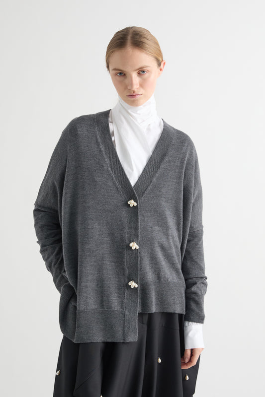 Person wearing a gray cardigan with white buttons on a white background