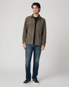 Man wearing a brown suede jacket and blue jeans 