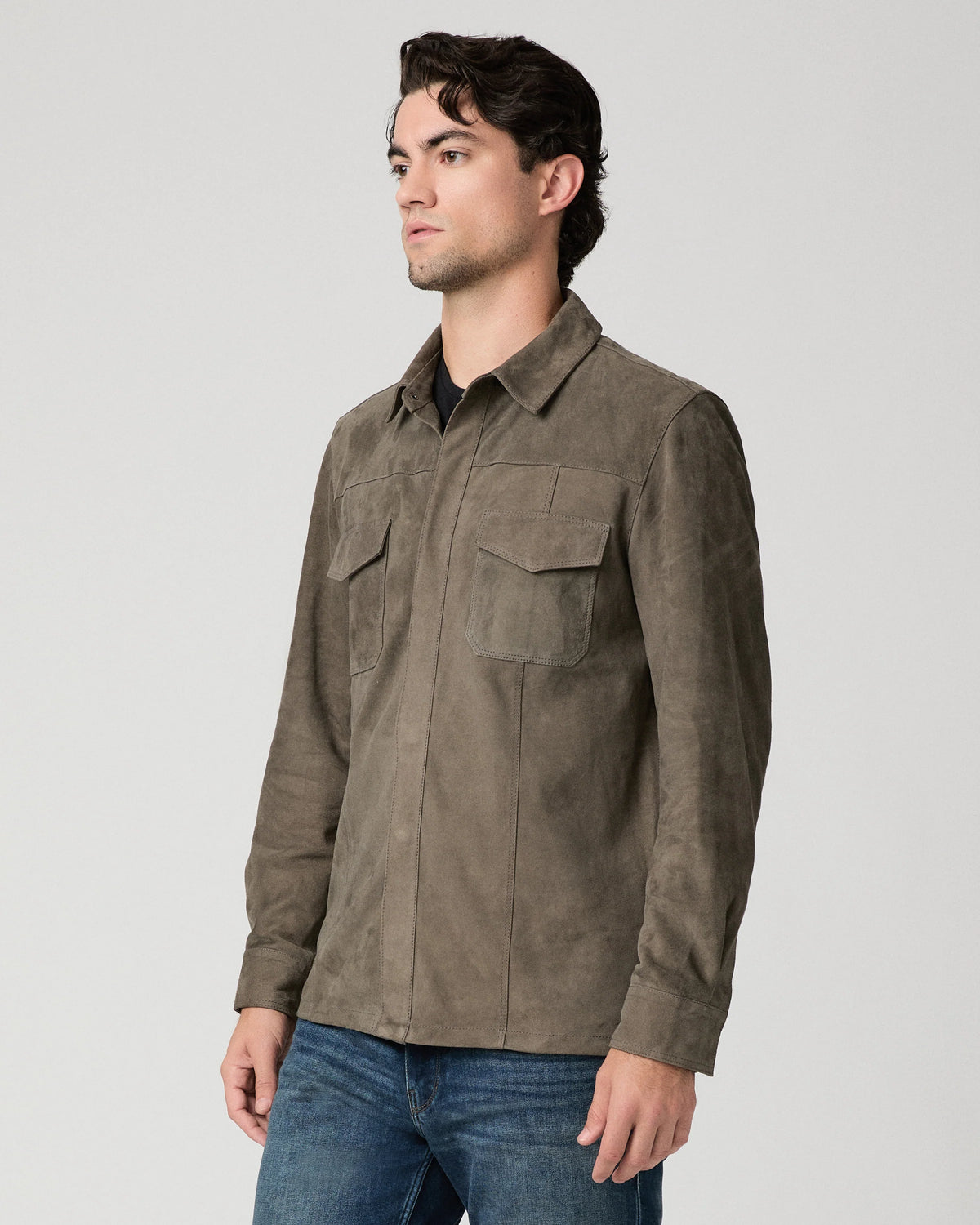 Man wearing a brown suede jacket and blue jeans side view