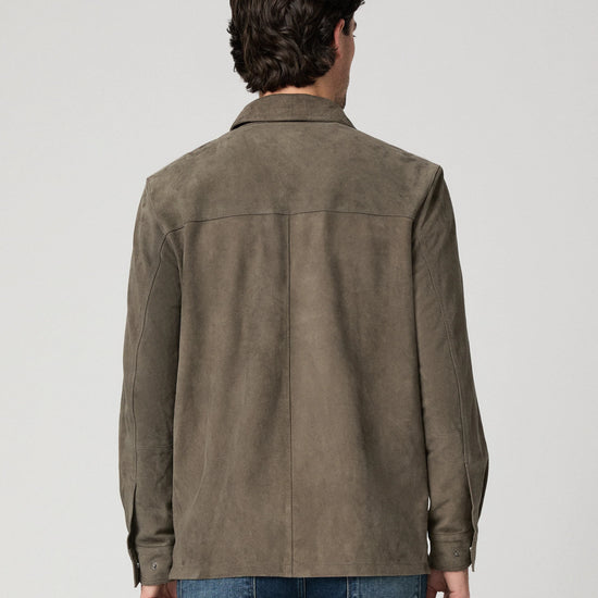 Man wearing a brown suede jacket and blue jeans rear view