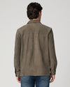 Man wearing a brown suede jacket and blue jeans rear view
