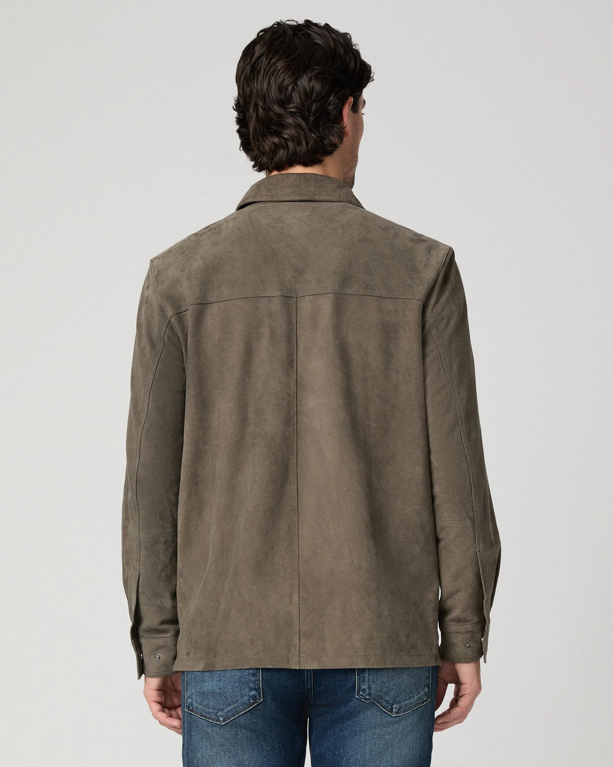 Man wearing a brown suede jacket and blue jeans rear view