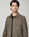 Man wearing a brown suede jacket and blue jeans close up