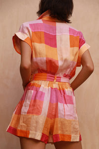 Short playsuit with elasticated waist in pink and orange check linen fabric with chunky buttons and classic collar