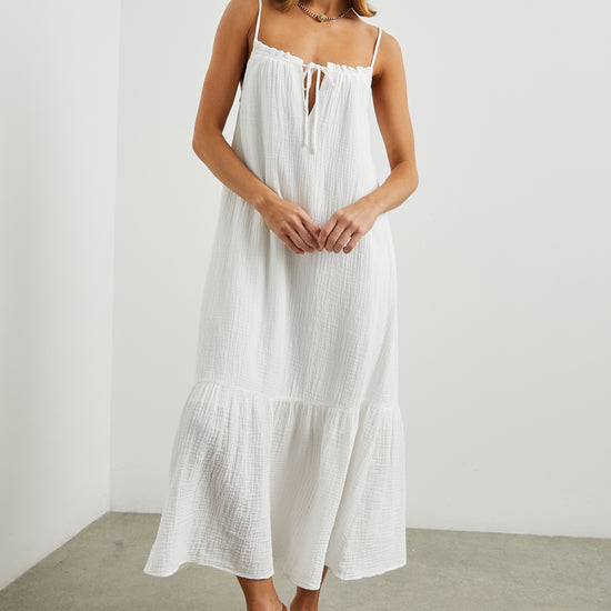 Strappy white cotton muslin dress with tie detail at the neckline and a deep ruffle at the hem