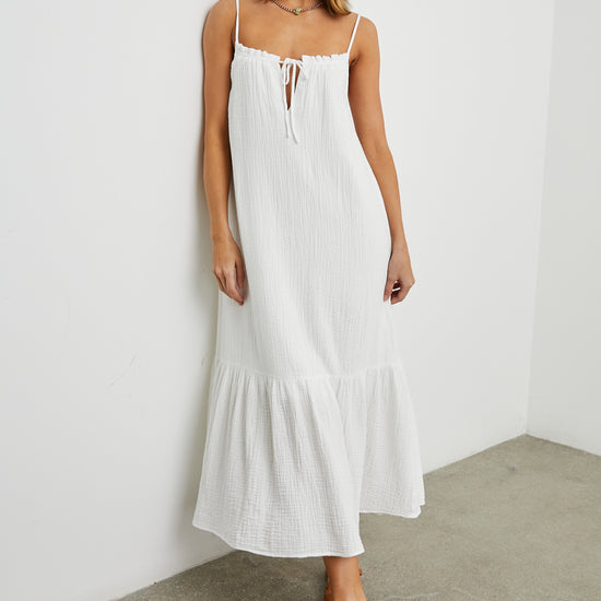 Strappy white cotton muslin dress with tie detail at the neckline and a deep ruffle at the hem