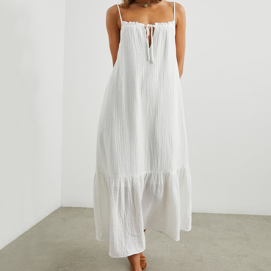 Strappy white cotton muslin dress with tie detail at the neckline and a deep ruffle at the hem