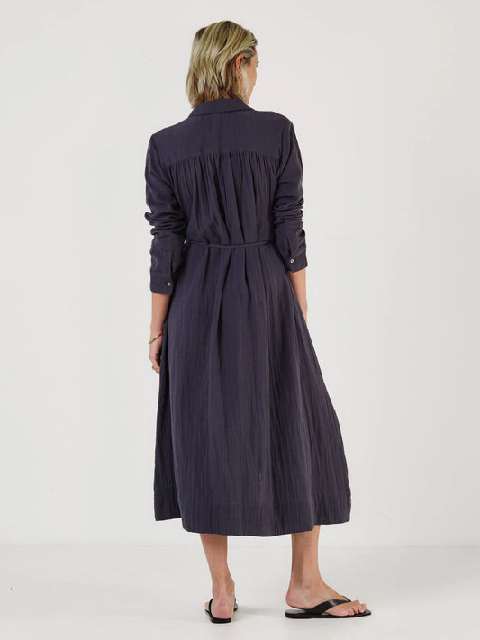 Woman wearing a long dark blue dress by Mondo Corsini on a white background. Rear View.