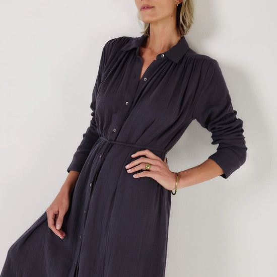 Woman wearing a long dark blue dress by Mondo Corsini on a white background. Close up