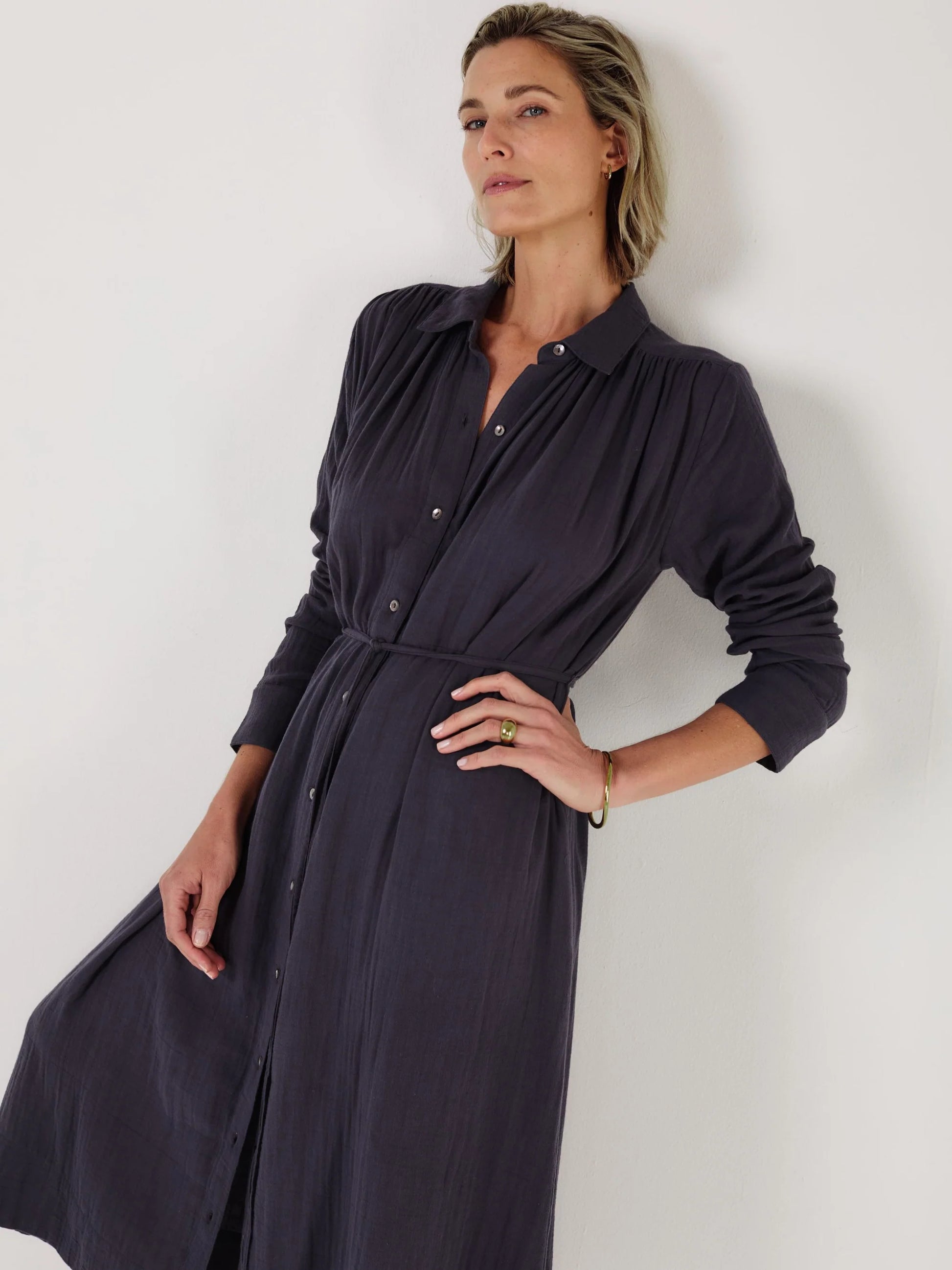 Woman wearing a long dark blue dress by Mondo Corsini on a white background. Close up