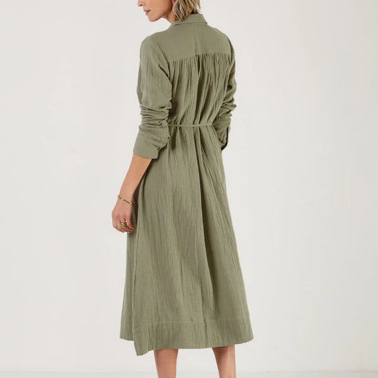 Woman wearing a green dress by Mondo Corsini with a white background. Rear view
