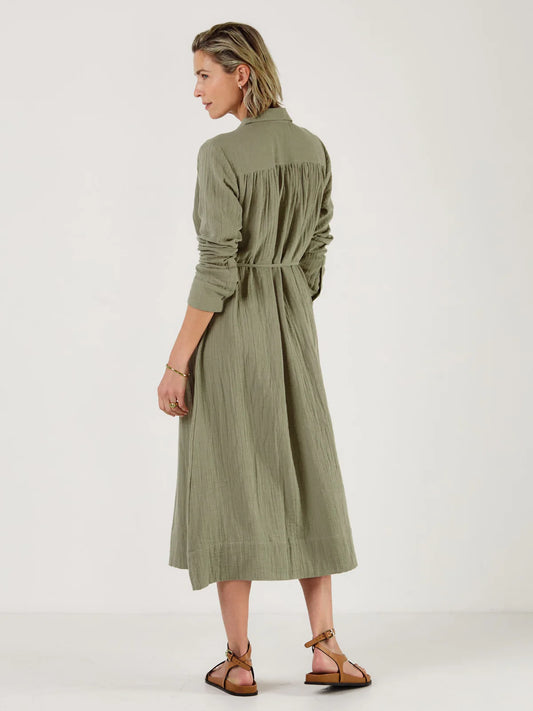 Woman wearing a green dress by Mondo Corsini with a white background. Rear view