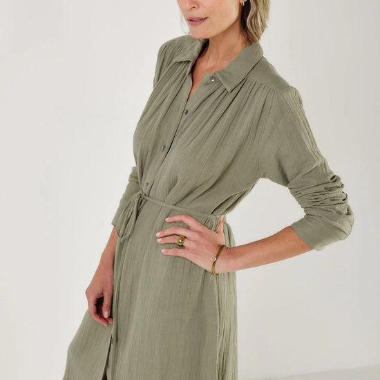 Woman wearing a green dress by Mondo Corsini with a white background. Close up