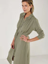 Woman wearing a green dress by Mondo Corsini with a white background. Close up
