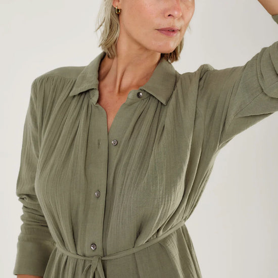Woman wearing a green dress by Mondo Corsini with a white background. Close up straight on