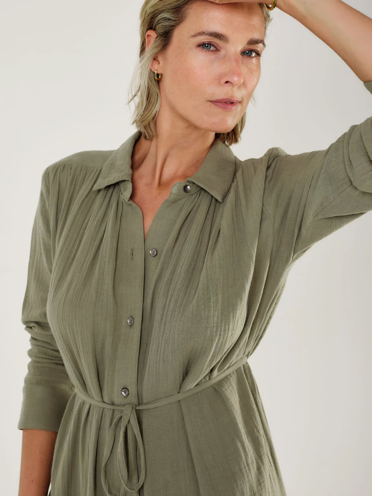 Woman wearing a green dress by Mondo Corsini with a white background. Close up straight on