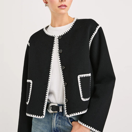 black collarless jacket with white piping/edging  and 2 front patch pockets 