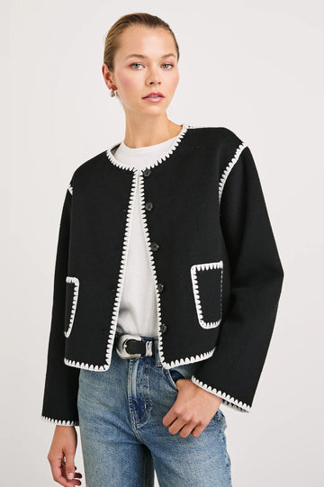 black collarless jacket with white piping/edging  and 2 front patch pockets 