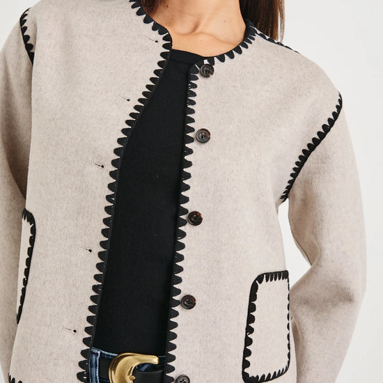 oatmeal collarless jacket with black piping and 2 front patch pockets  close up