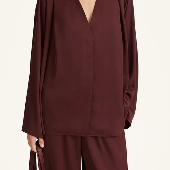Person wearing a burgundy outfit with a plain background