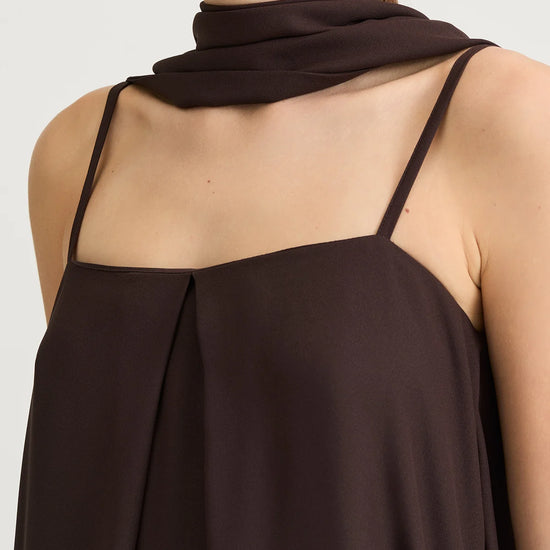 Brown sleeveless top worn by a person on a white background