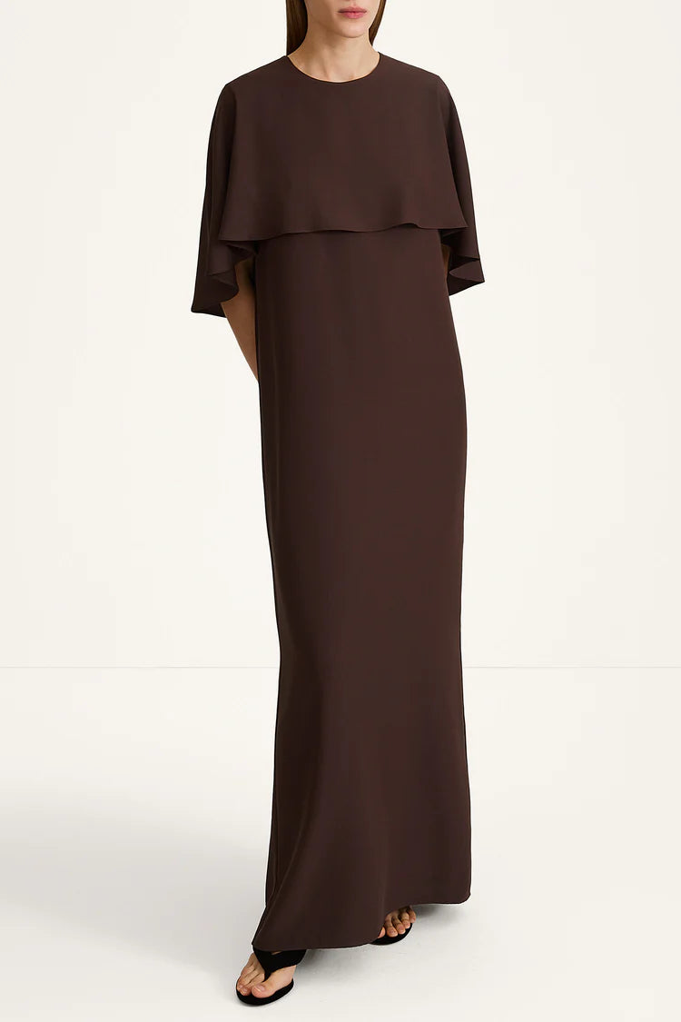 A woman modeling a floor-length dark brown dress with a layered ruffle neckline and short flutter sleeves, photographed against a plain off-white studio background.