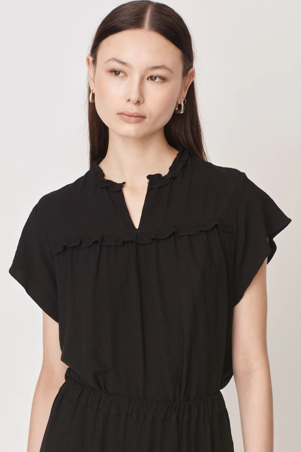Short sleeved black top with notch neck and ruffle detail in a textured fabric