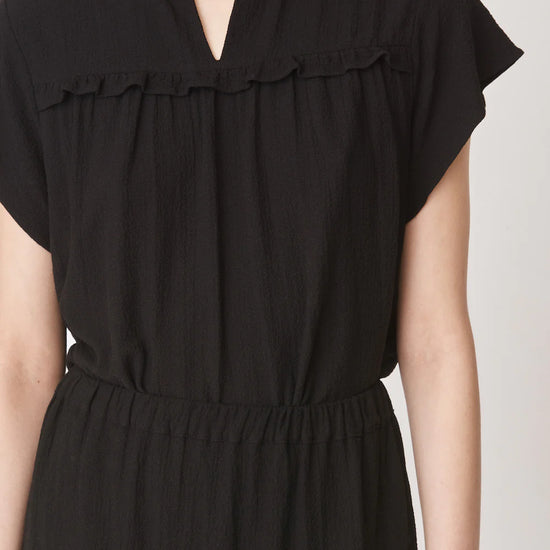 Short sleeved black top with notch neck and ruffle detail in a textured fabric