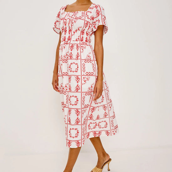 Woman wearing a red and white patterned dress on a plain background