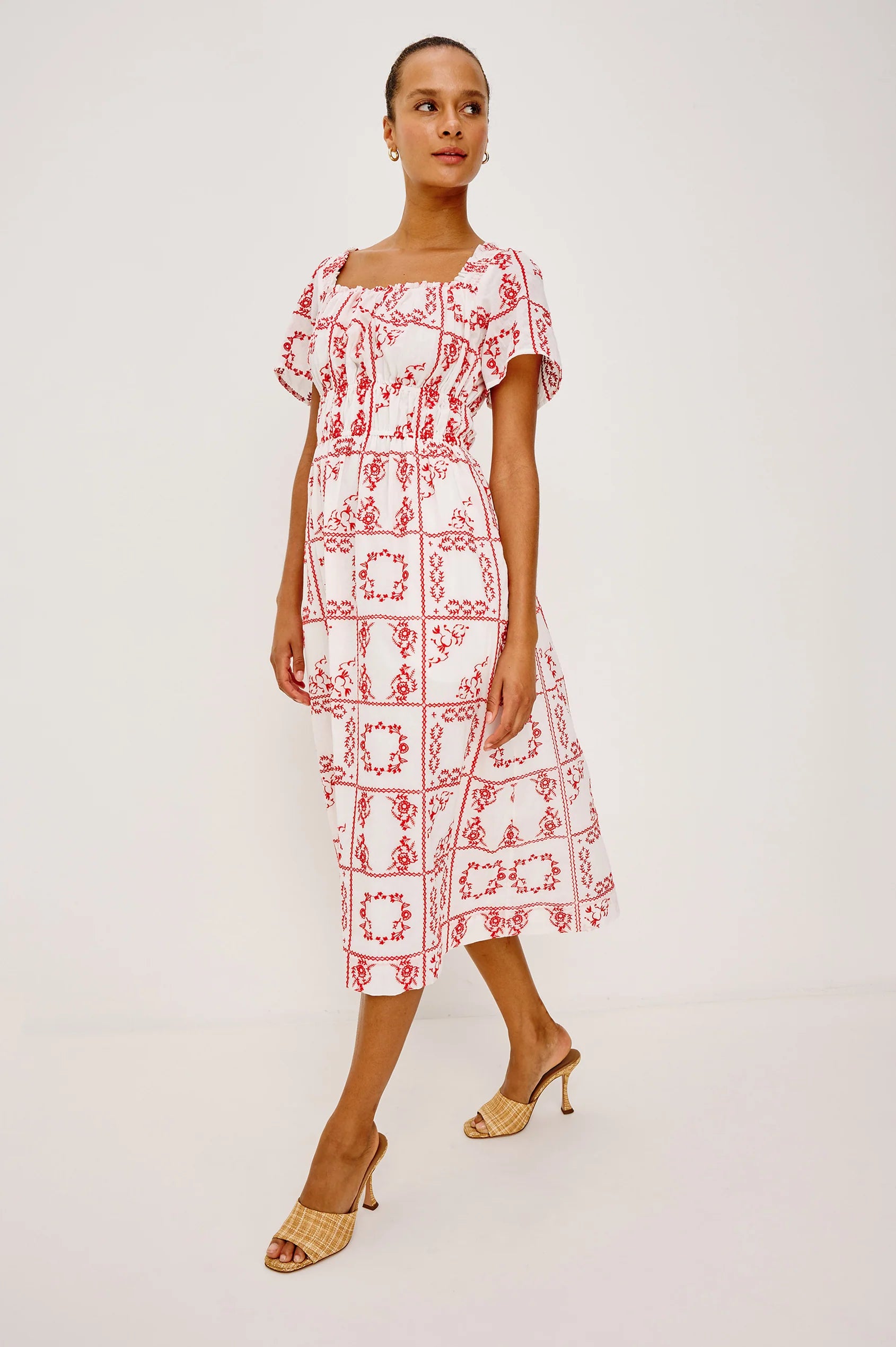 Woman wearing a red and white patterned dress on a plain background