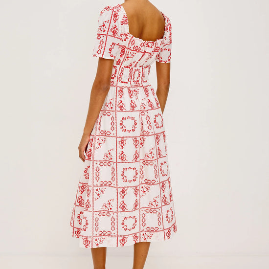 Rear view of Woman wearing a red and white patterned dress on a plain background