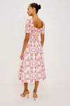 Rear view of Woman wearing a red and white patterned dress on a plain background