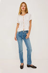 Woman wearing a white lace top by Rails and blue jeans on a plain background