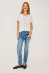 Woman wearing a white lace top and blue jeans on a plain background full outfit