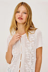 Woman wearing a white lace top by Rails against a plain background close up