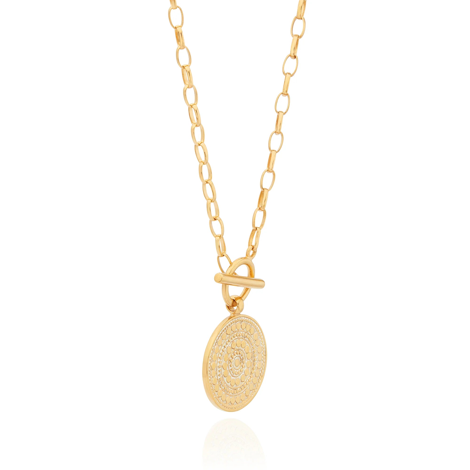 Gold necklace with toggle fastening and coin shaped pendant featuring dot work
